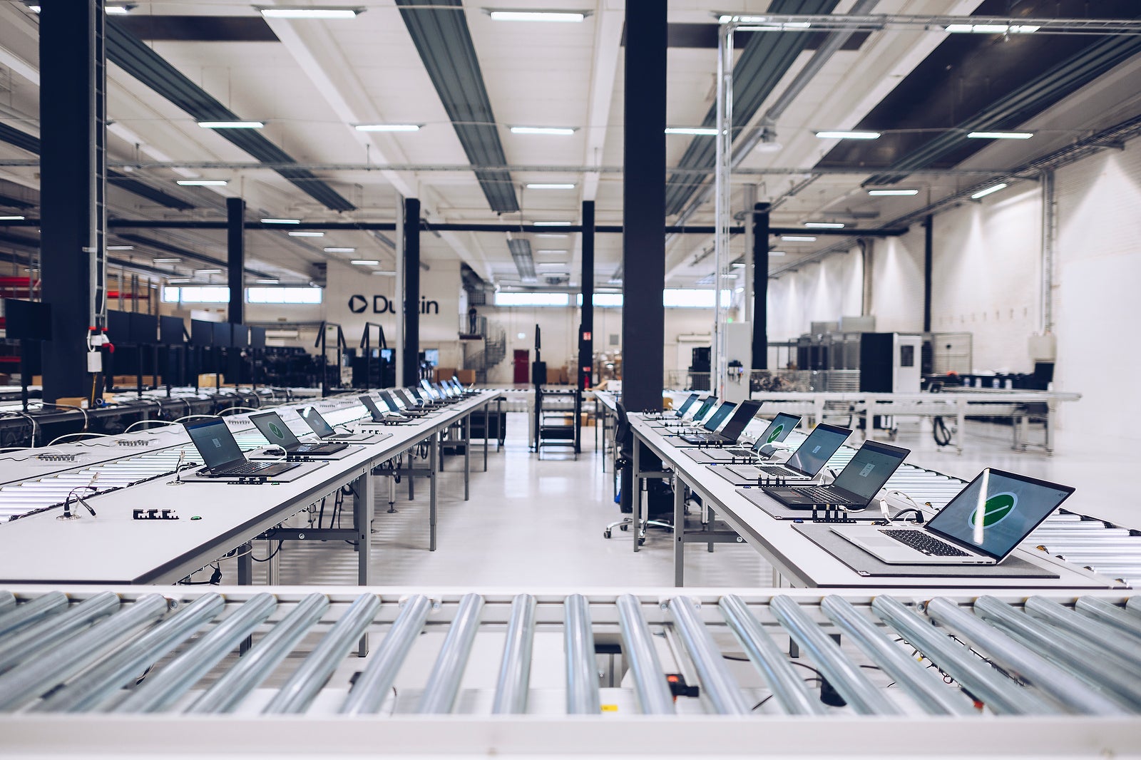 Ett modernt lagerföretag med långa arbetsband och elektroniska enheter uppradade längs väggarna.