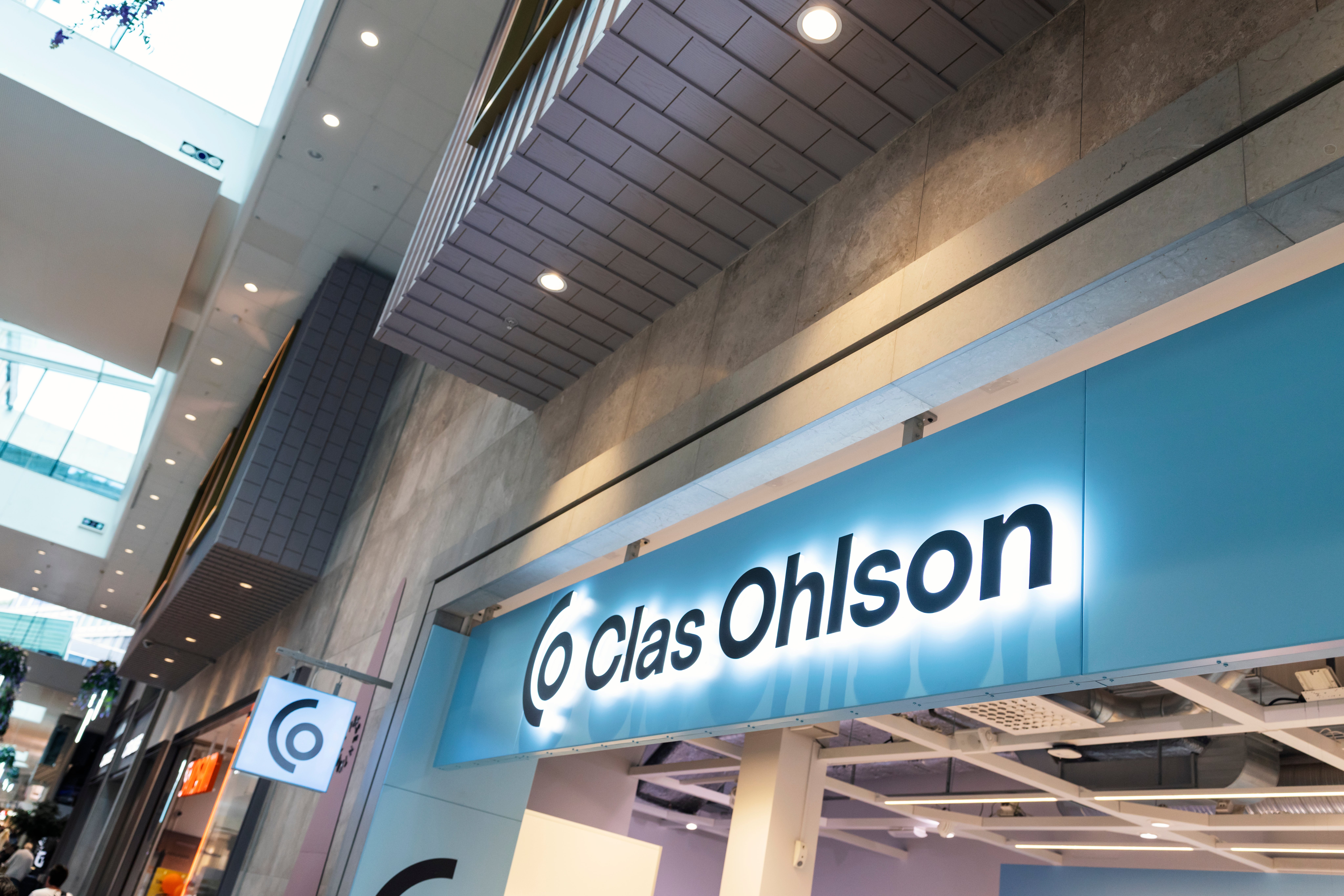 Ljusblå butiksskylt med texten Clas Ohlson i ett modernt köpcentrum