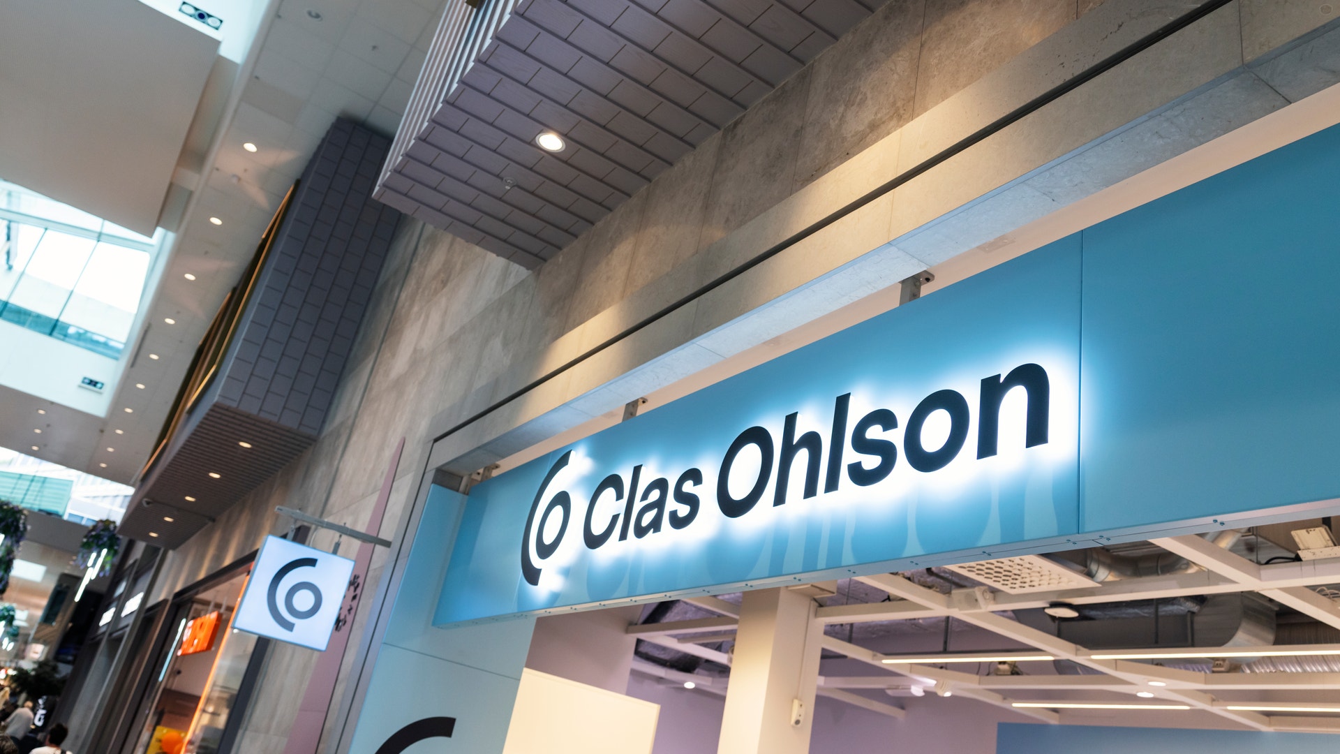 Ljusblå butiksskylt med texten Clas Ohlson i ett modernt köpcentrum