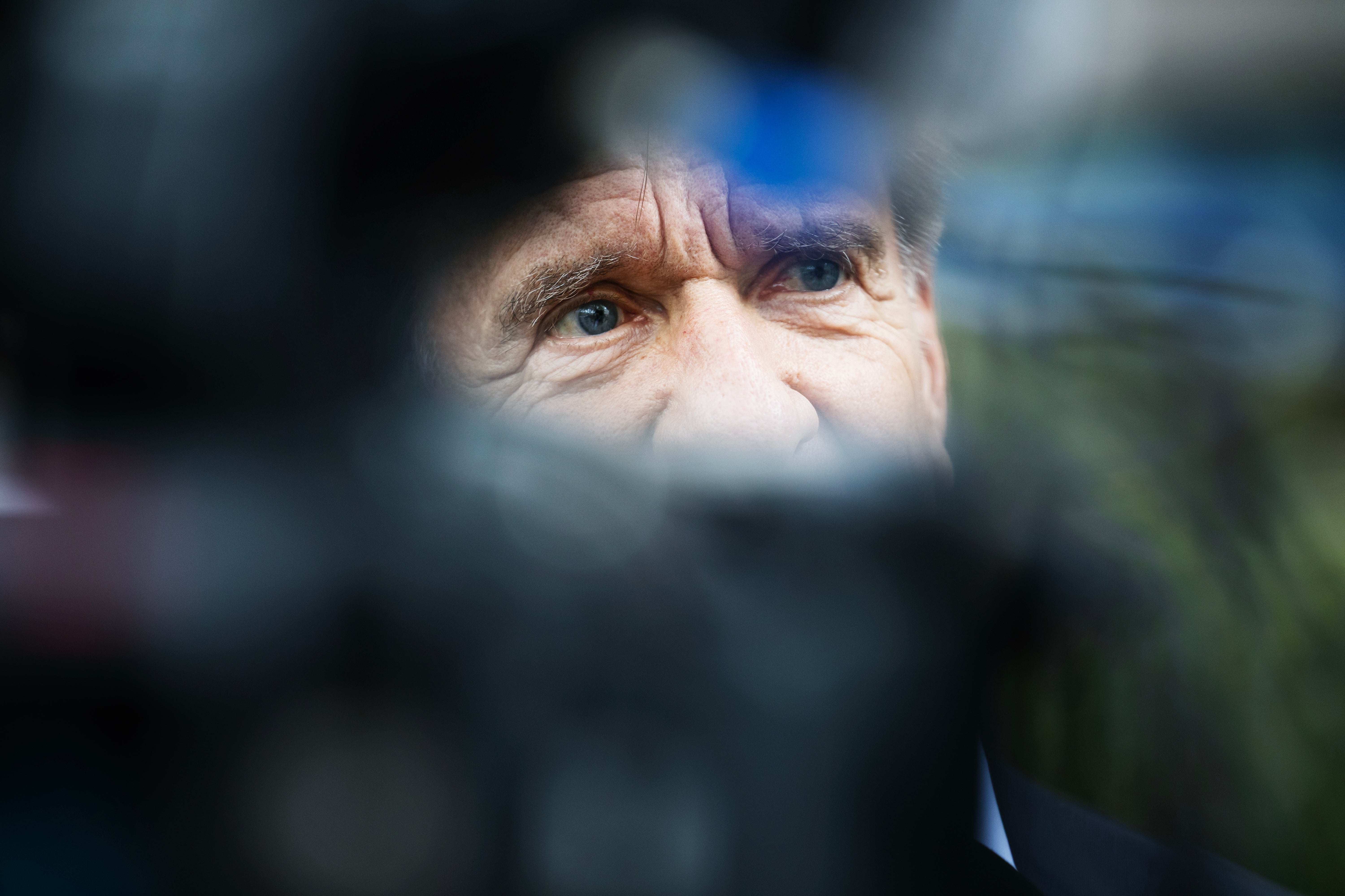 En man syns i närbild, fotograferad genom kamerautrustning som är oskarp i förgrunden.