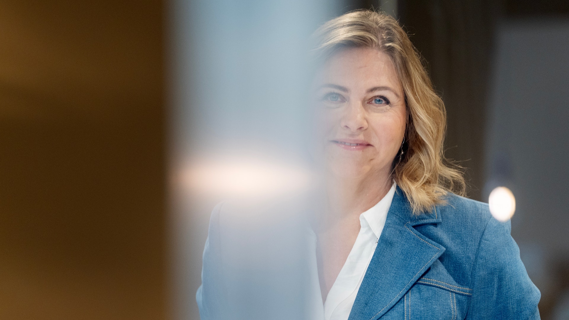 Porträtt av en kvinna i blå kavaj och vit skjorta mot suddig bakgrund