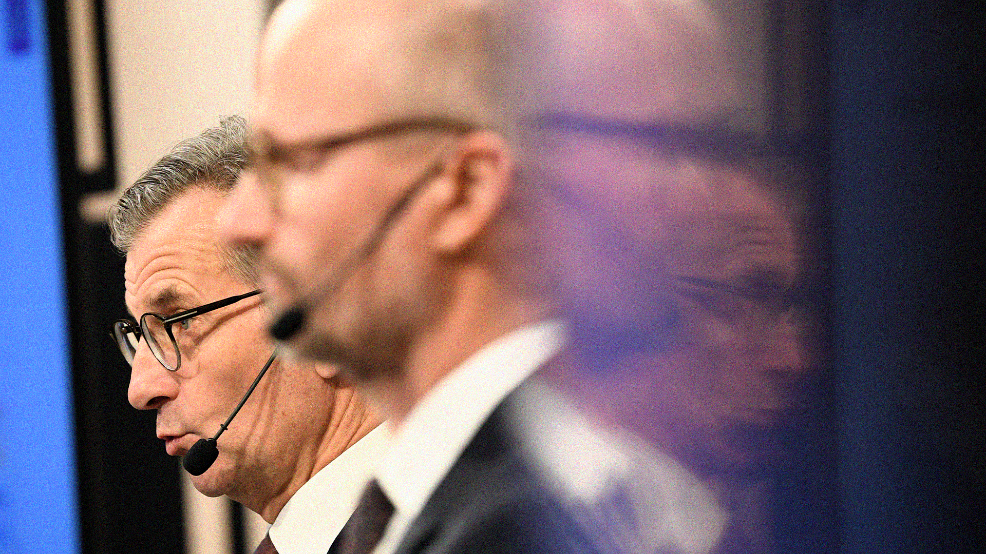 Man med glasögon och headset-mikrofon som presenterar på en scen