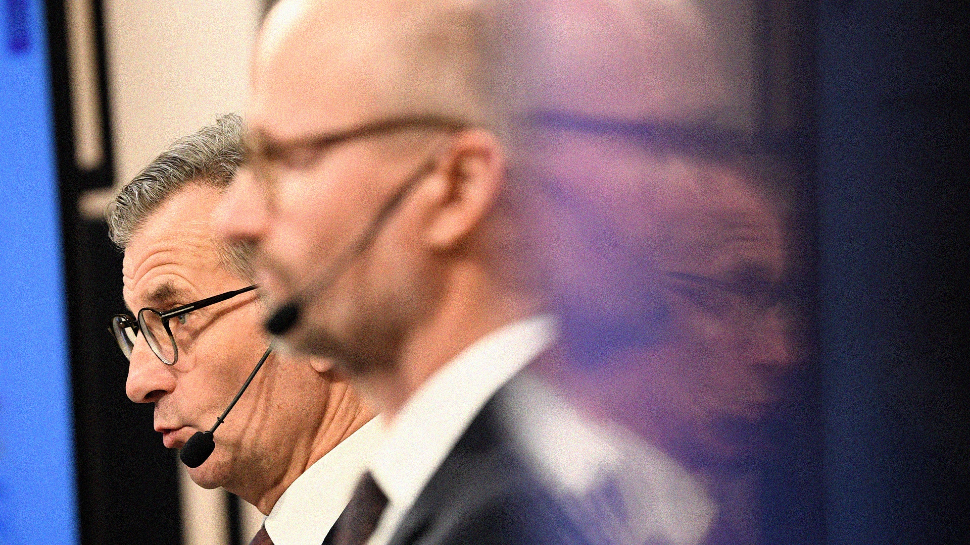 Man med glasögon och headset-mikrofon som presenterar på en scen