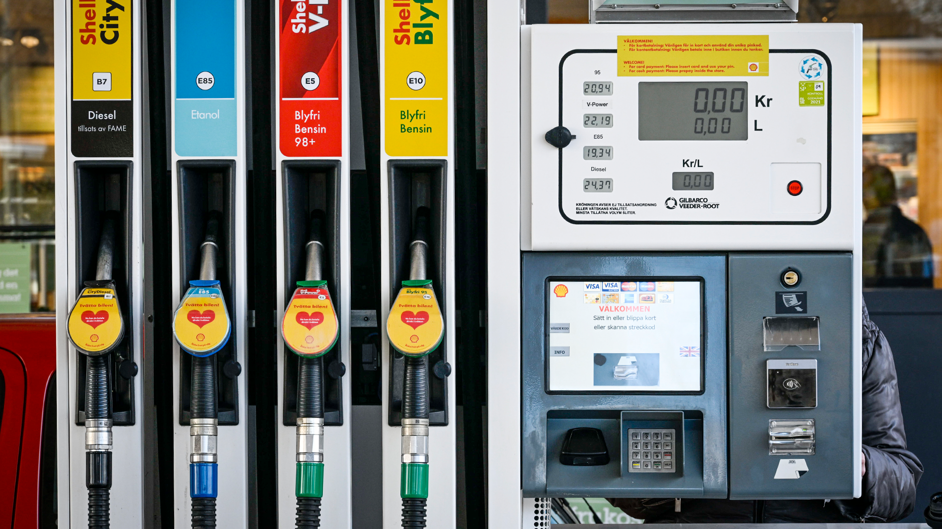 Fyra bensinpumpar med olika bränsletyper och ett betalningsterminal på en bensinstation.