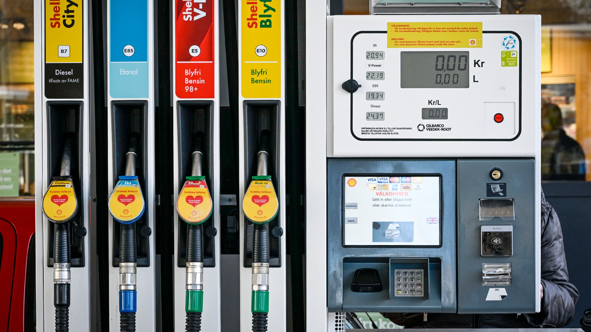 Fyra bensinpumpar med olika bränsletyper och ett betalningsterminal på en bensinstation.