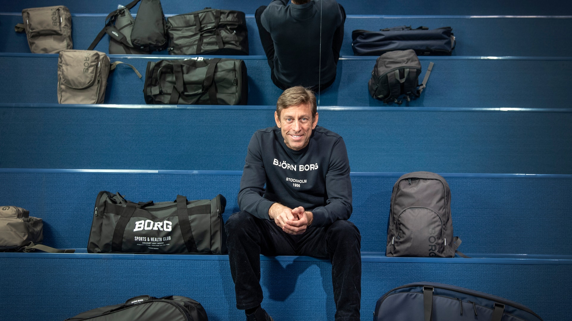 Henrik Bunge, vd Björn Borg sitter på en läktare omgiven av Björn Borg-varor.