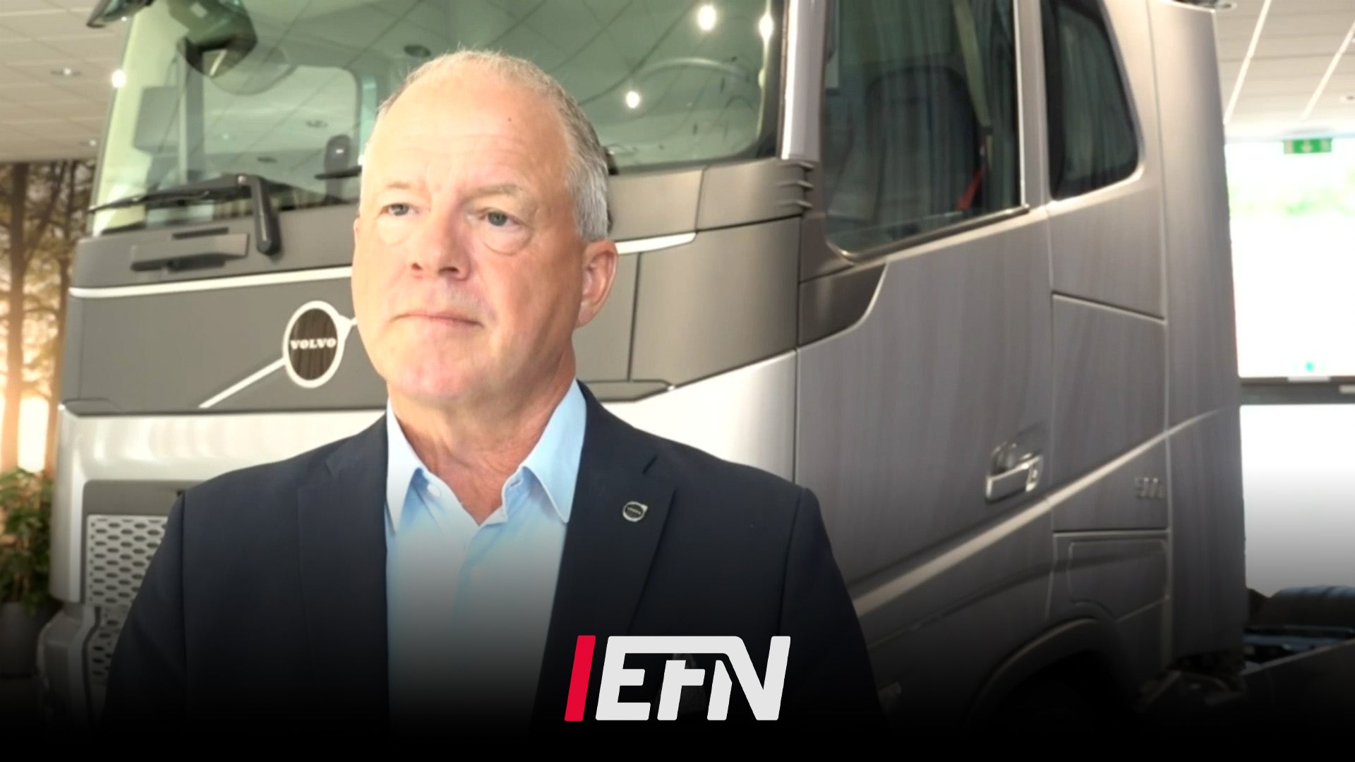 Man i kostym framför en Volvo-lastbil med EFN-logotyp.