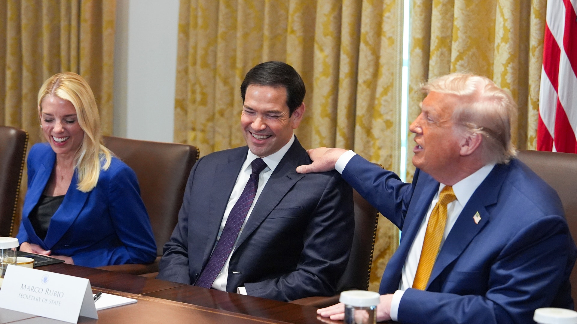 Donald Trump klappar Marco Rubio på axeln vid ett samtal i ett konferensrum i vita huset.