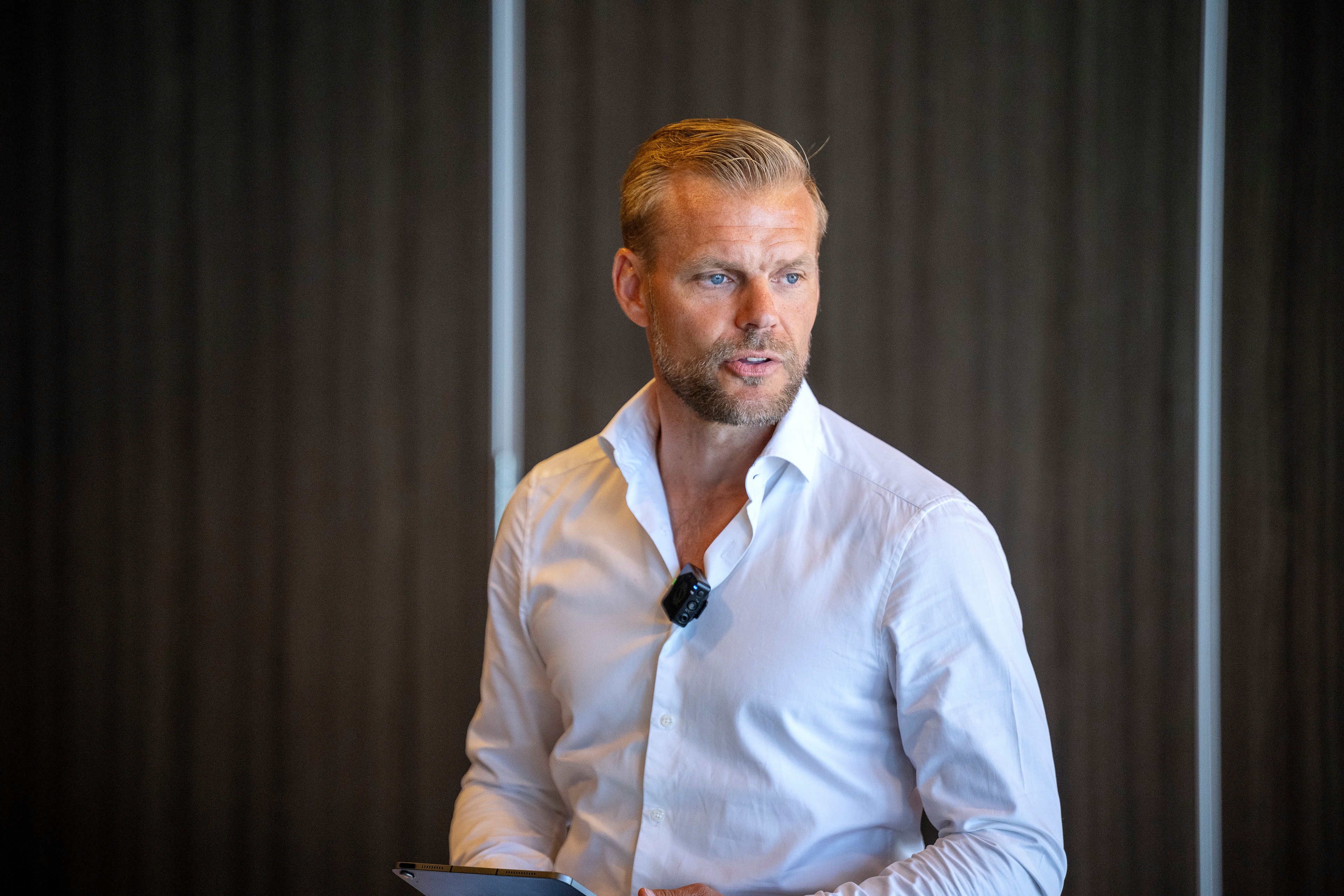 En man i vit skjorta presenterar inför publik. Johan Arneng