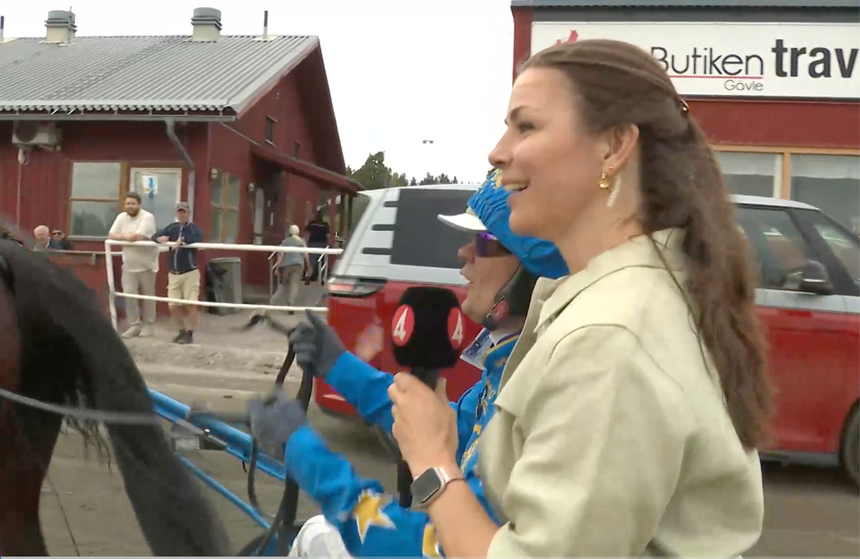 En kvinna håller i en blå och röd leksaksfigur utomhus framför en röd byggnad.