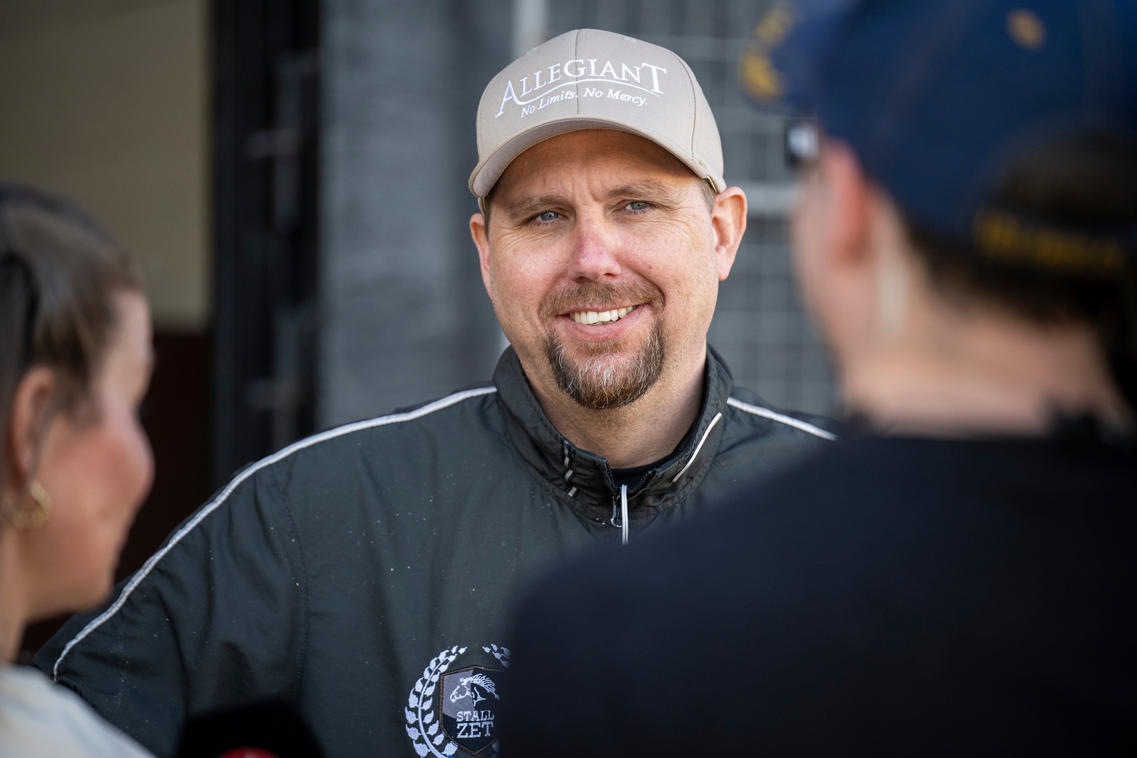 Porträtt av en man med vit keps och mörkblå jacka som står och pratar med andra personer.

Daniel Reden