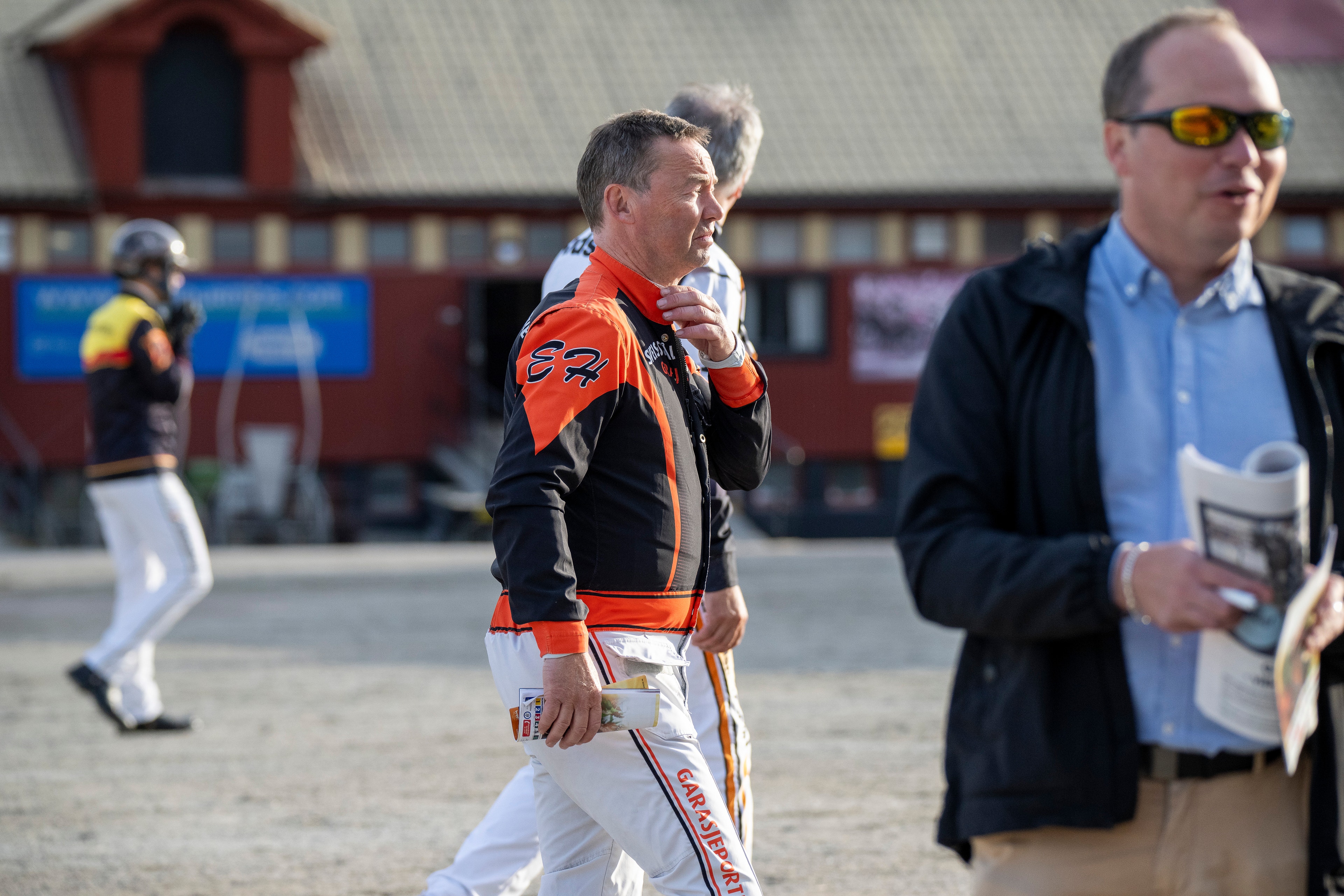 En ung baseballspelare i orange och svart uniform går tillsammans med en vuxen man vid en baseballplan. En fotograf syns i bakgrunden.
Eirik Höitomt