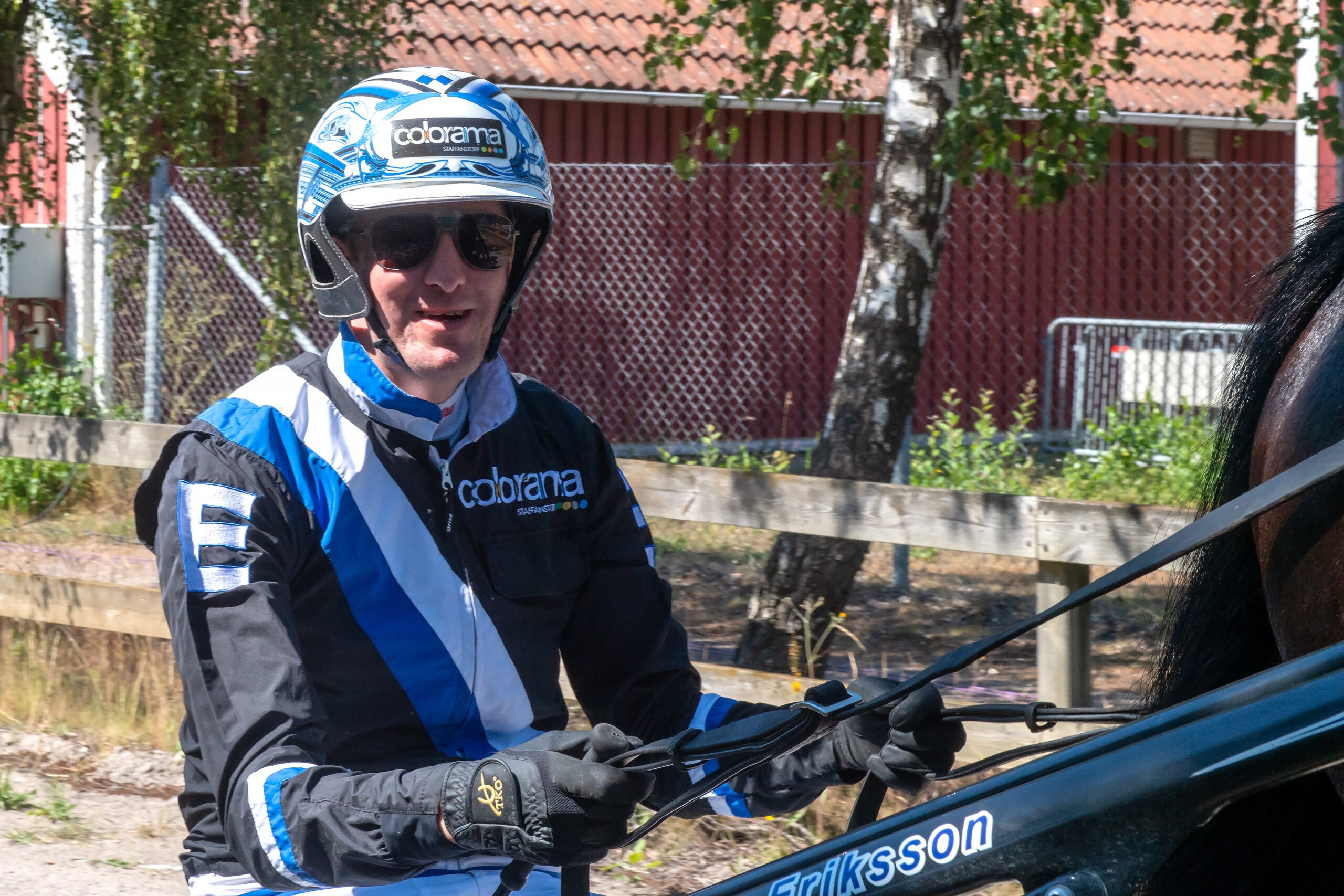 Person i blå och svart motorcykelkläder och hjälm sitter på en motorcykel utomhus.