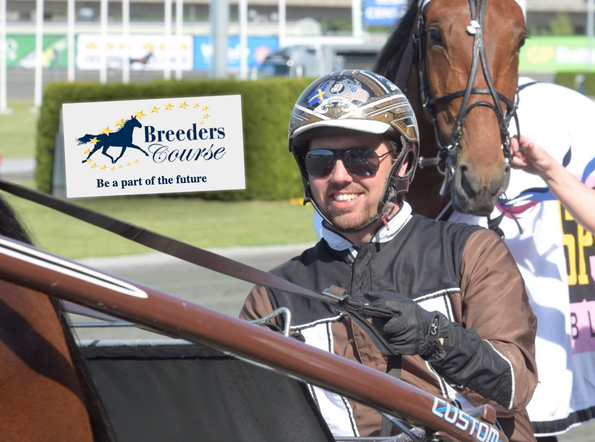 En jockey i svart ridkläder och hjälm står bredvid en brun häst på Breeders Course racerbana.