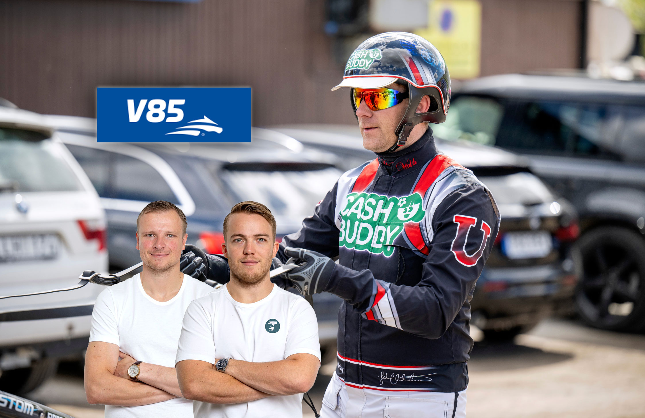 Två män i vita t-shirts står tillsammans med en cyklist i full cykelutrustning inklusive hjälm och solglasögon. V85-logon syns i bakgrunden tillsammans med parkerade bilar.