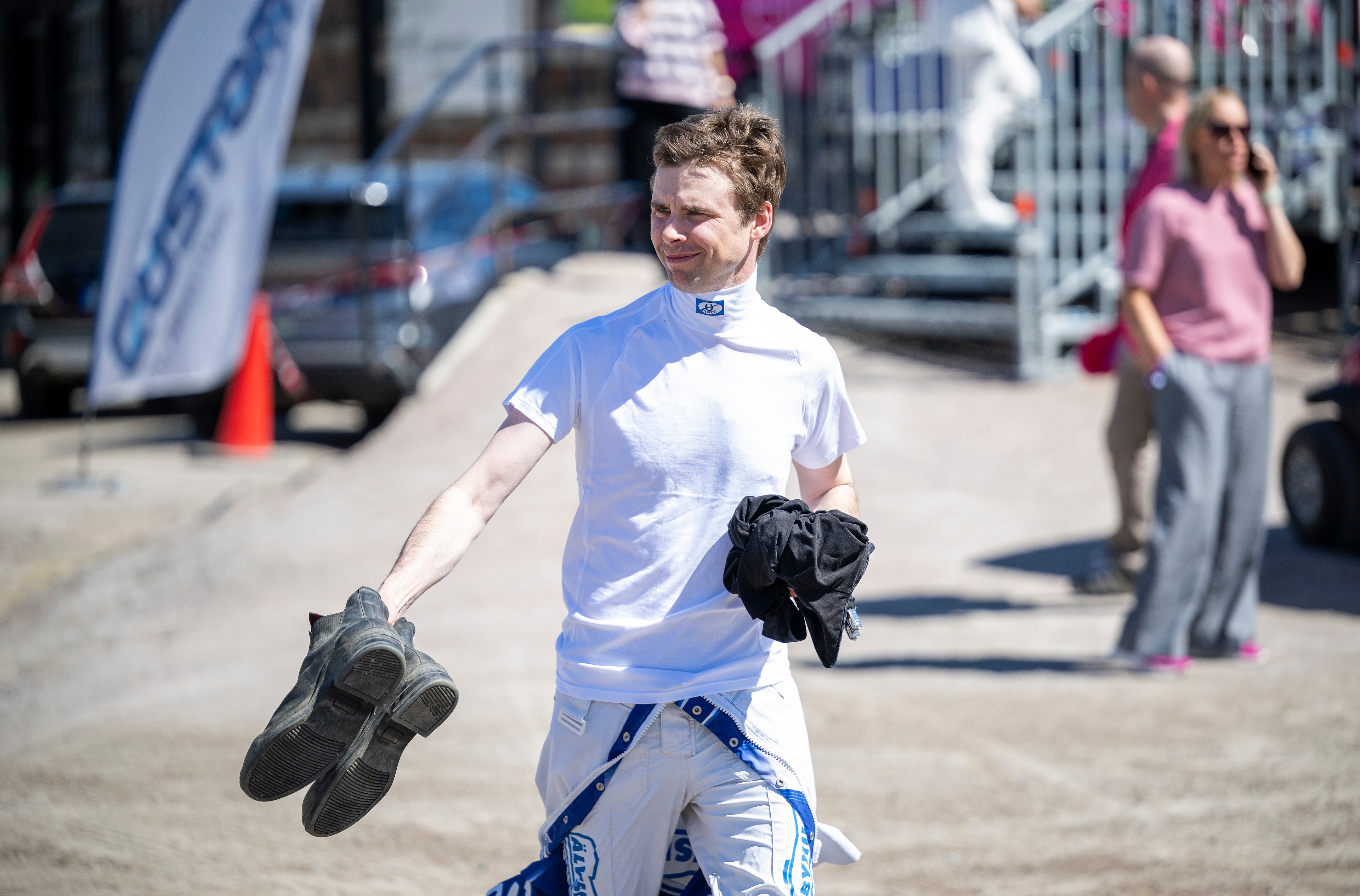 En motocrossförare i blå och vit utrustning håller upp sina smutsiga stövlar efter ett lopp vid Solvalla.