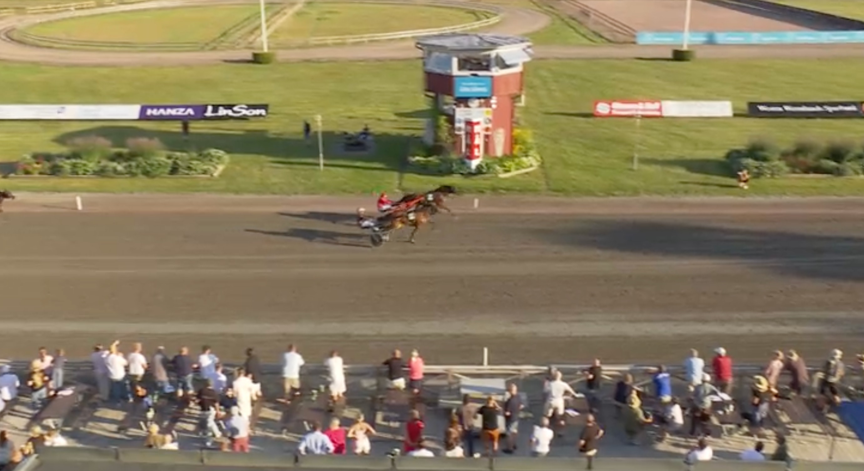 Luftfoto från en galoppracebana med en häst och jockey som rider på banan medan publik står längs sidan.