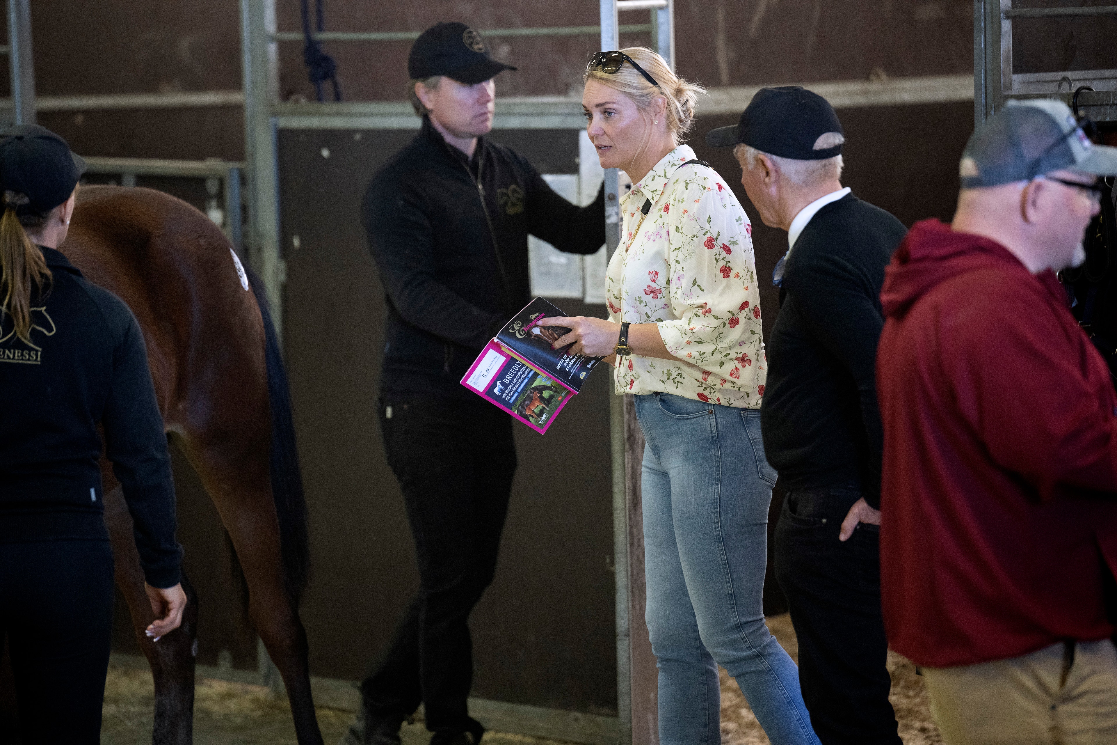 Grupp av människor vid en häst under en tävling på Solvalla. En person i gul skjorta håller i ett papper medan andra står omkring i stallen.